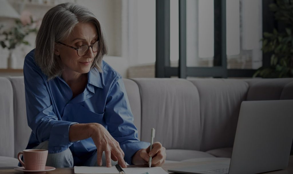 A background image for LIG Solutions of a woman signing a sheet of paper