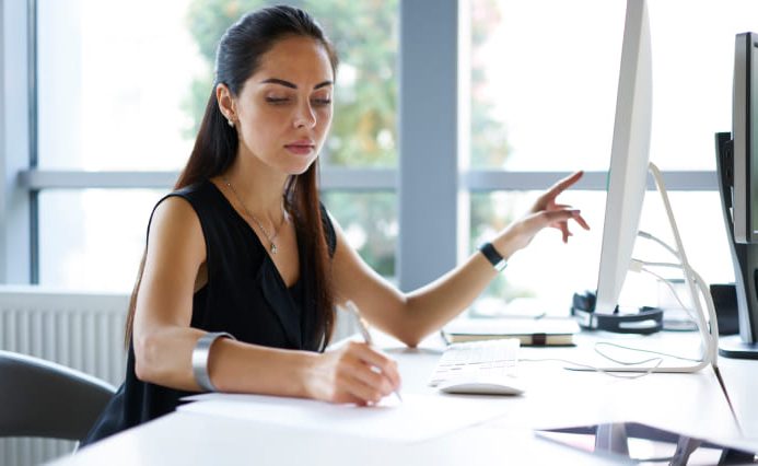 Logo designer in Miami adds notes while at her desk