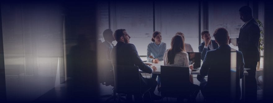 A team sit around a desk in a meeting room