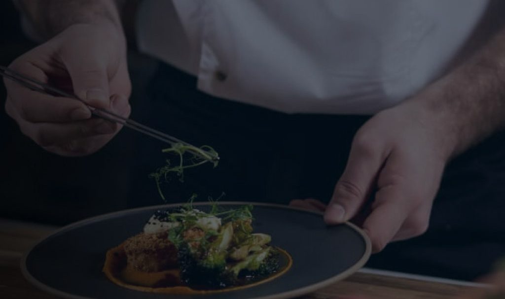 A background image for Ventura Foods of a chef preparing a meal